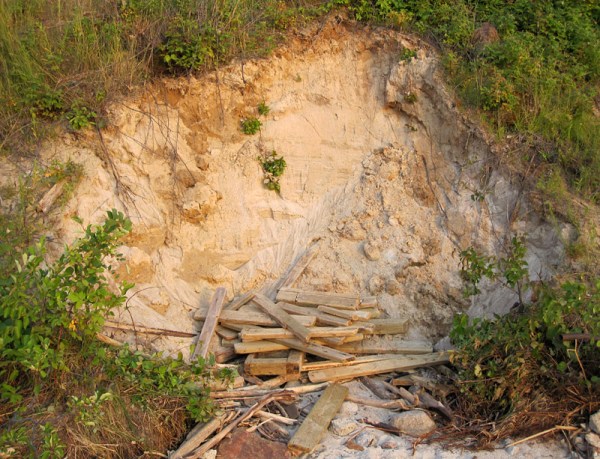 I suspect that the wood at the base of this slope is the remnant of someone's stairs to the beach. 