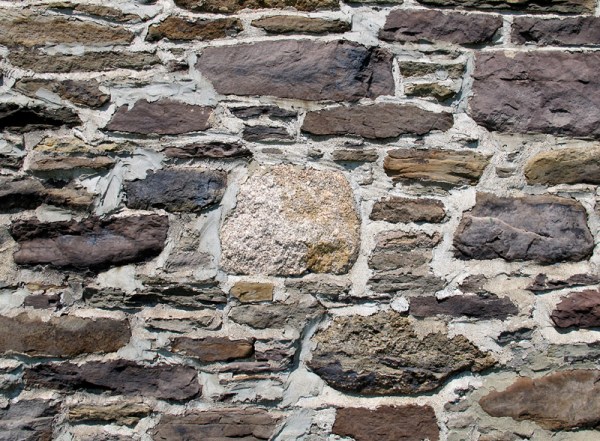 A piece of granitic fieldstone is incorporated into a wall.
